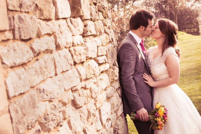 Bride & Groom kissing leaning on old wall