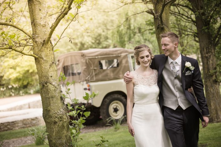 Bride & Groom walking through woods with Landrover