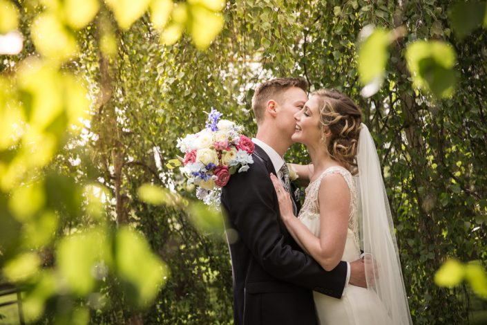 Bride & Groom kissing under trees